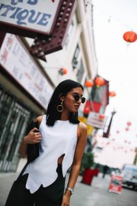 LA Blogger Tania Sarin in Chinatown wearing asymmetrical top, revolve gold hoop earrings, and green wide leg pant